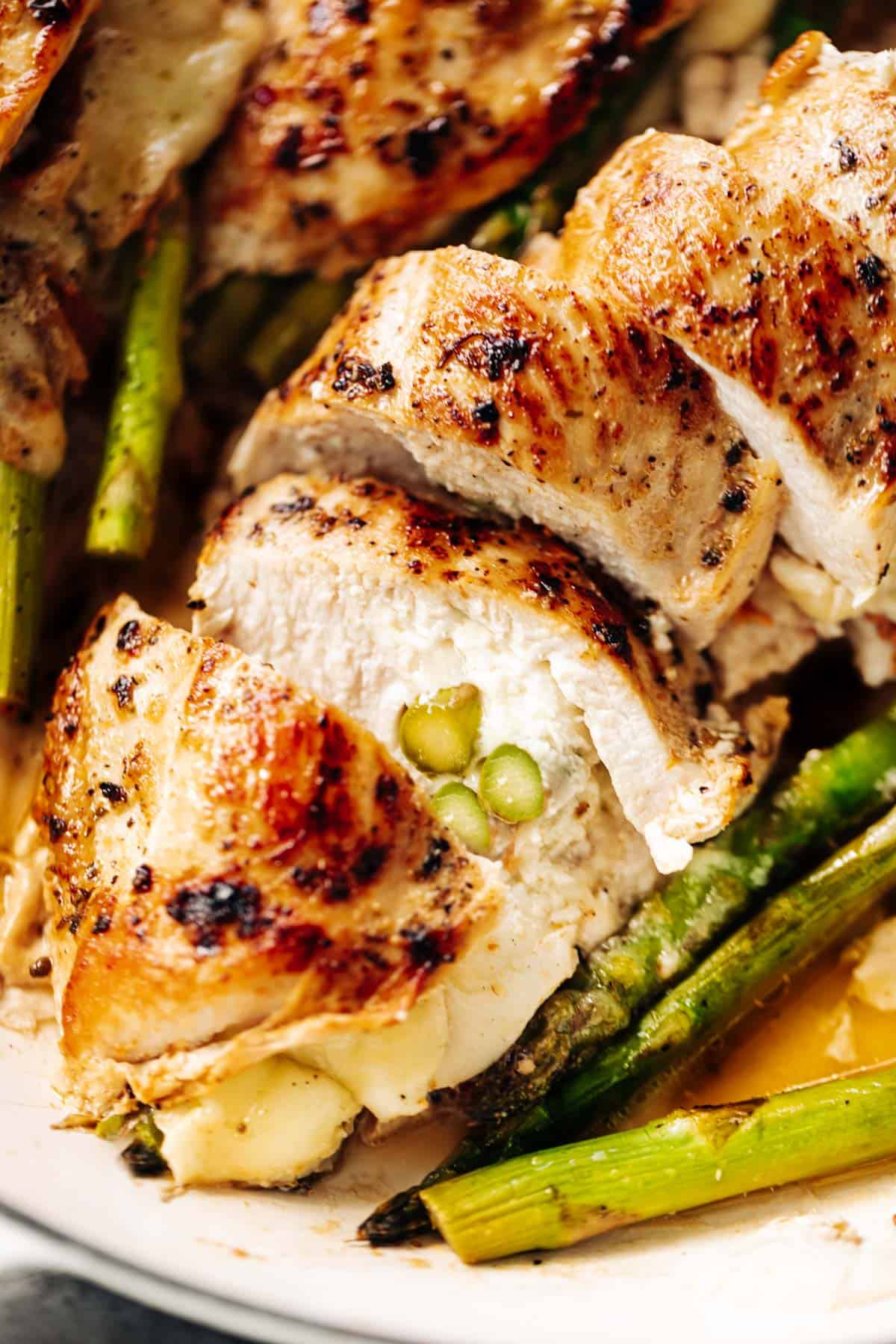 A close up image of one asparagus and mozzarella cheese stuffed chicken breast sliced open to see the inside | cafedelites.com