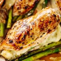 Four asparagus and mozzarella cheese stuffed chicken breasts in a white casserole dish | cafedelites.com