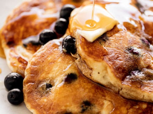 Three Blueberry Pancakes served on a plate with melted butter and maple syrup | cafedelites.com