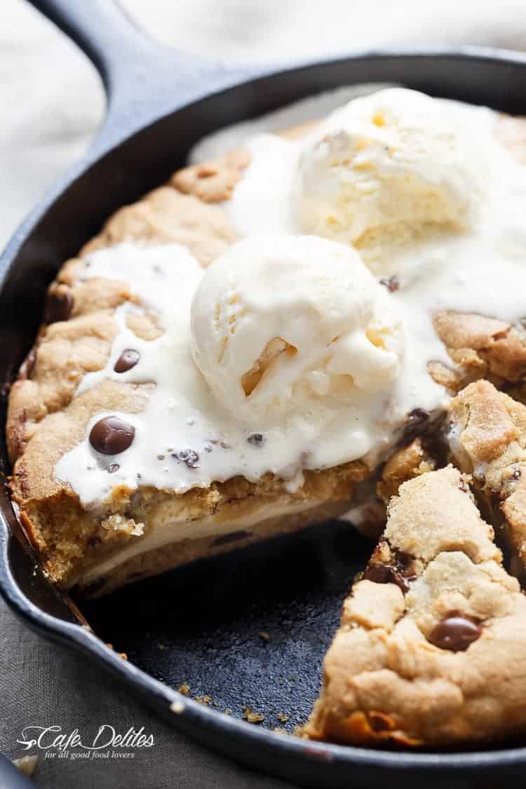 A crispy, soft Cheesecake Stuffed Chocolate Chip Skillet Cookie! Layers of cookie dough and cheesecake is the ultimate dessert for cheesecake/cookie lovers! | https://cafedelites.com