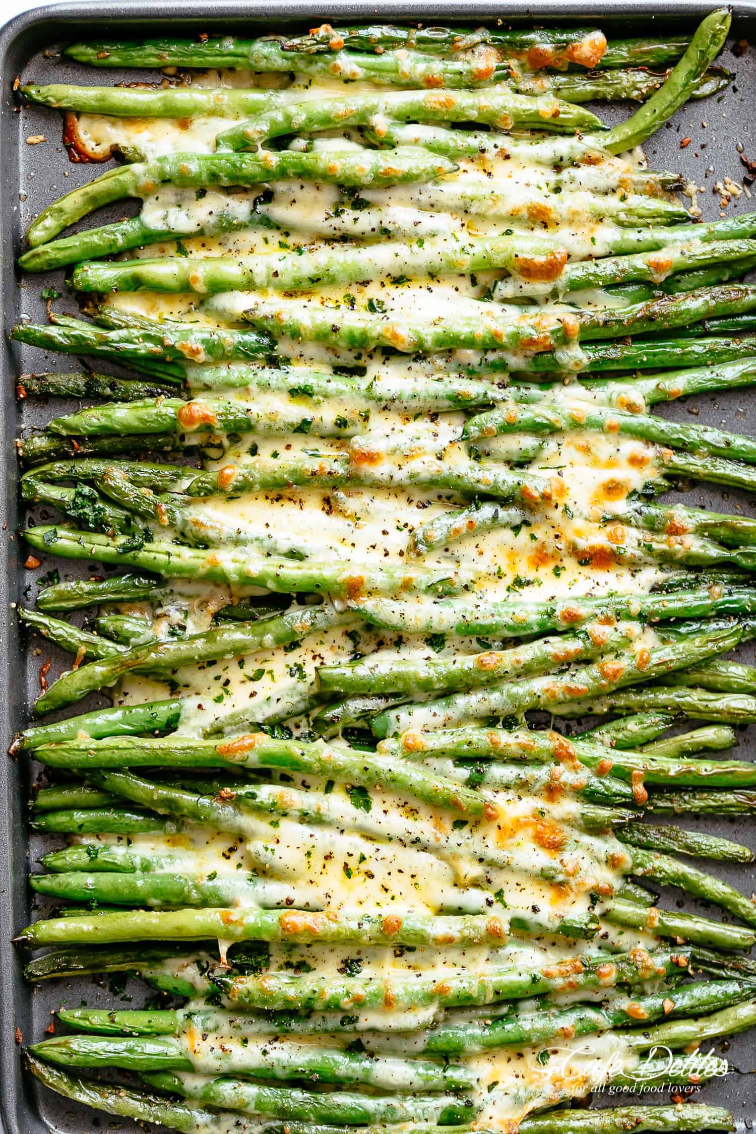 A tray of roasted green beans with melted cheese