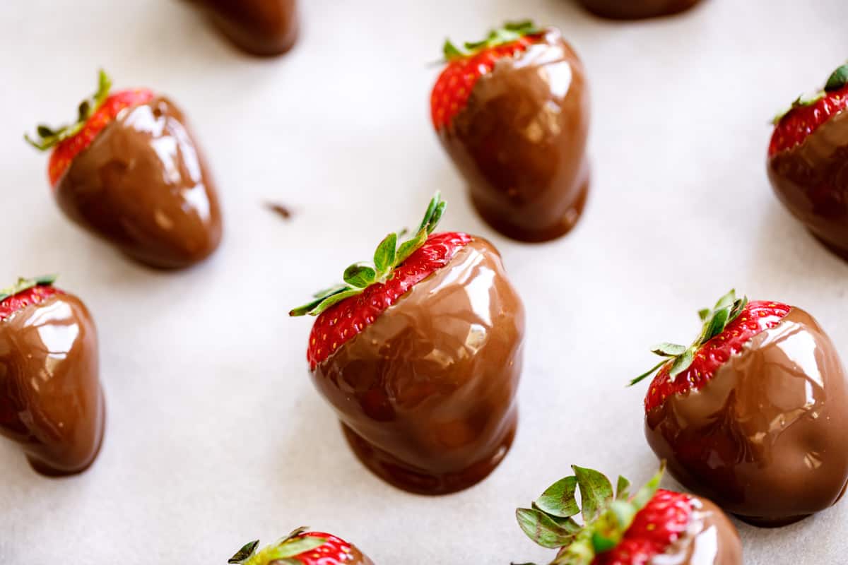 Strawberries on a baking sheet lined with baking paper with fresh chocolate dipped strawberries