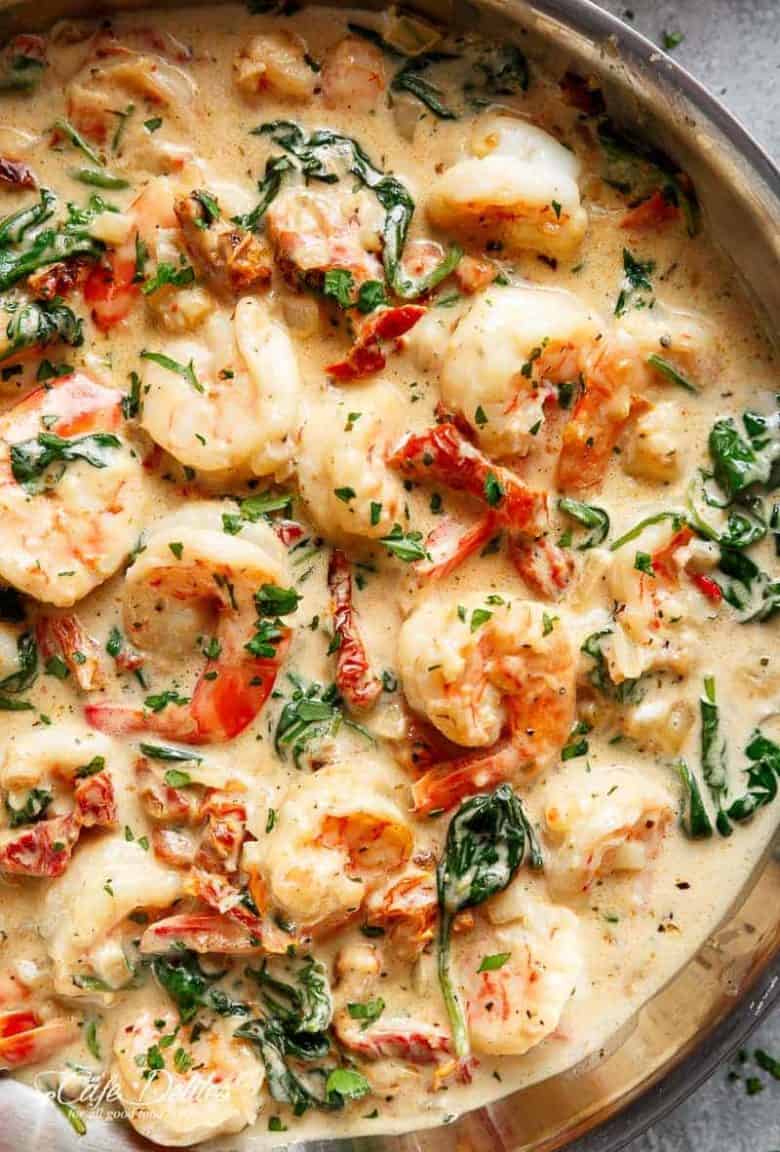 Creamy Garlic Butter Tuscan Shrimp coated in a light and creamy sauce filled with garlic, sun dried tomatoes and spinach! Packed with incredible flavours! | https://cafedelites.com