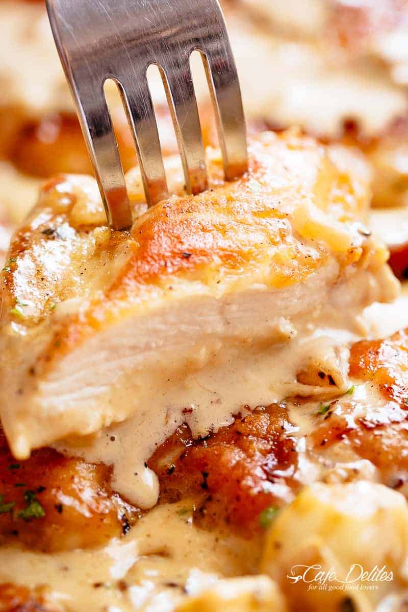 Chicken breasts are pan fried in until golden and crispy before being added to a mouth-watering garlic cream sauce! A silver fork pierces through a sliced piece of chicken! | cafedelites.com