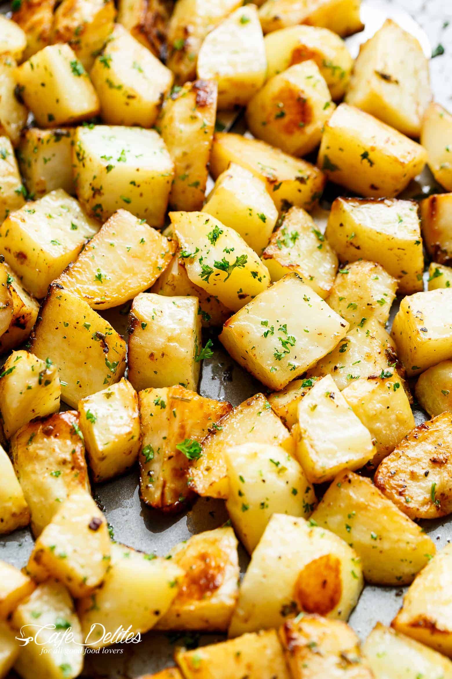 Crispy roasted potatoes on a baking sheet garnished with chopped parsley.