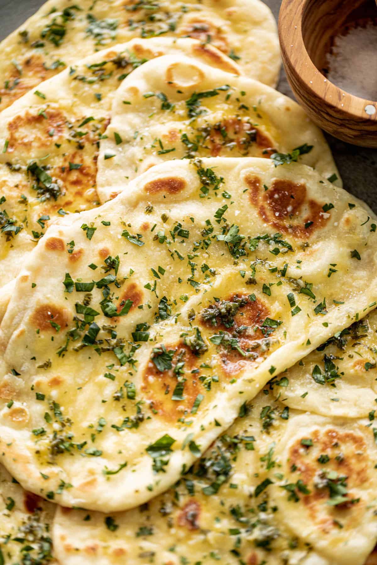Buttery Garlic Naan Breads on a plate with garlic butter and fresh chopped cilantro | cafedelites.com